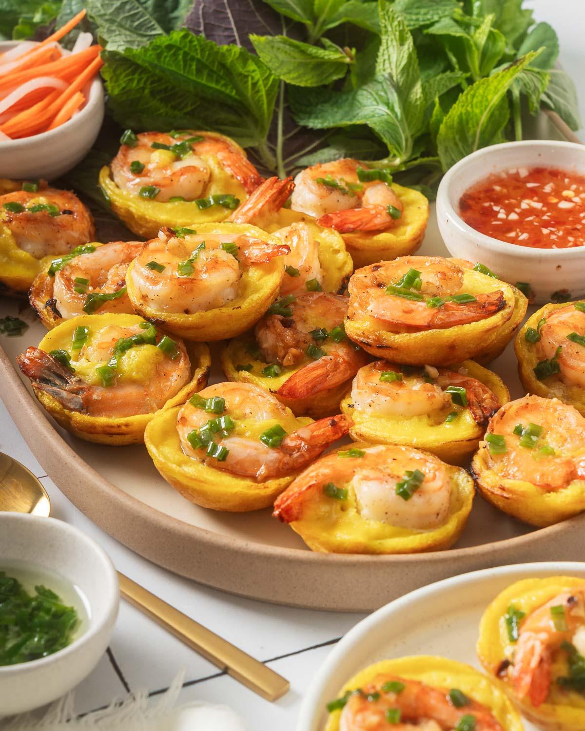 Two banh khot sitting on a bed of lettuce on a plate.